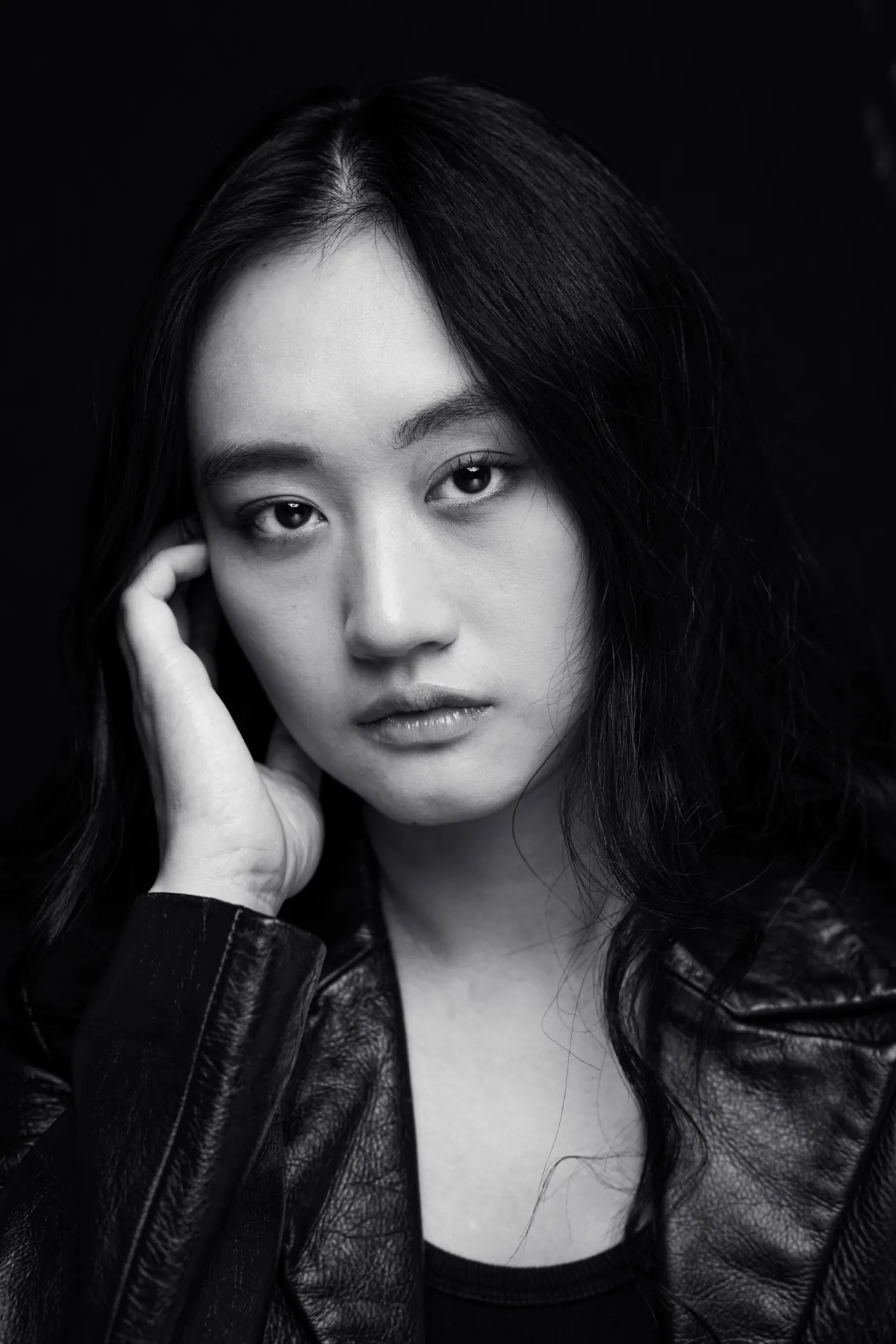 Black-and-white portrait of AJ Ho in a leather jacket against a dark background