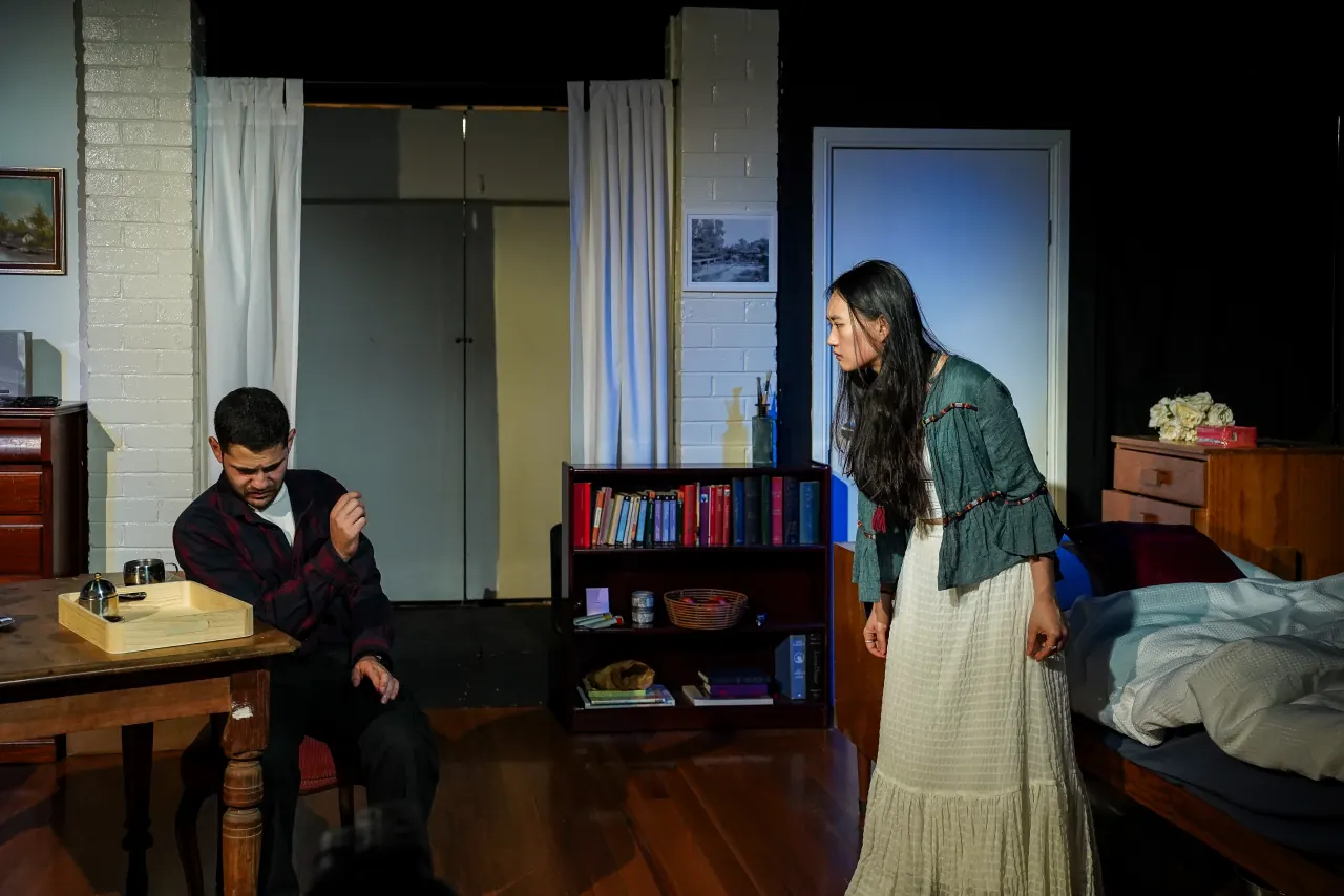 AJ Ho as Miranda Grey standing over Frederick, seated at a table, in The Collector
